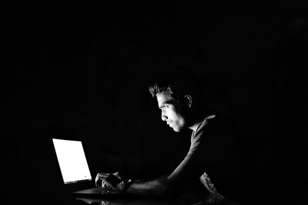 Man sitting in dark room on laptop