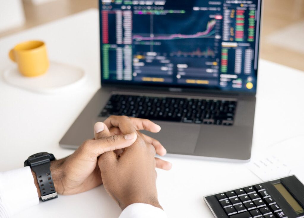 Hands folded on desk in front of a laptop with investment graph and Microsoft Copilot on the screen