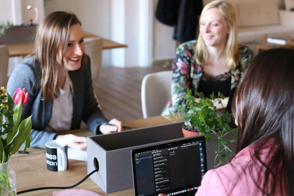 Three women sitting at a desk discussing AI in investment management