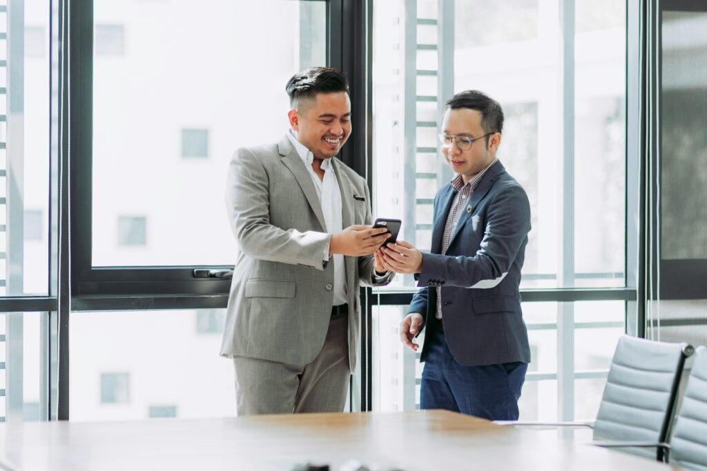 Two businessmen looking at federated learning programs on a phone in a bright office