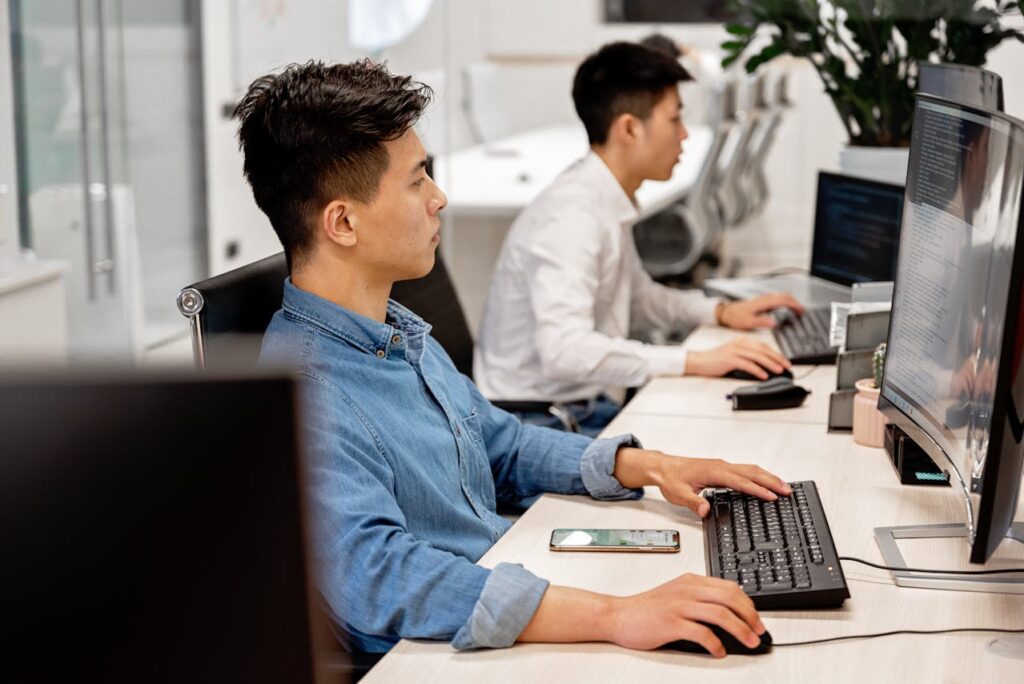 Men sitting at computers working on LCNC development in an office