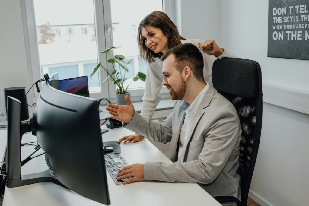 A man and woman in front of a desk working on DevSecOps on a computer