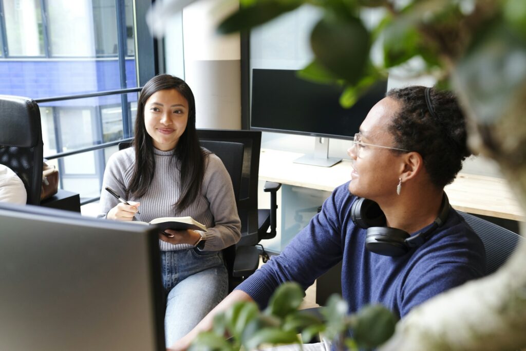 man and woman sitting in office chairs discussing hybrid cloud