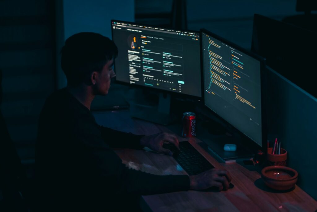 man in black long sleeve shirt implementing zero trust on a computer with two screens