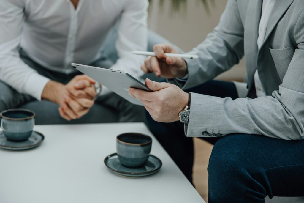Two men sitting at a table with a tablet discussing AI model governance