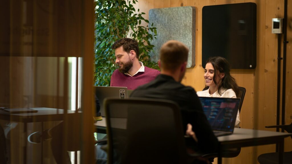 a group of professionals sitting at a table with laptops displaying workforce analytics information