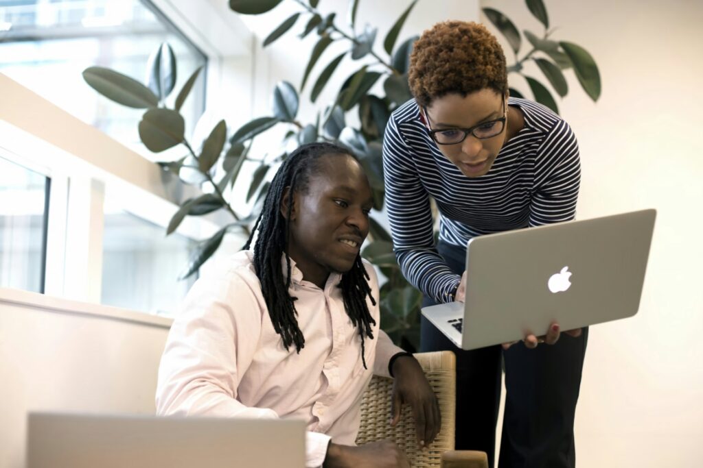 A woman shows a colleague her laptop screen and demonstrates how data mesh gives their team more ownership over data.