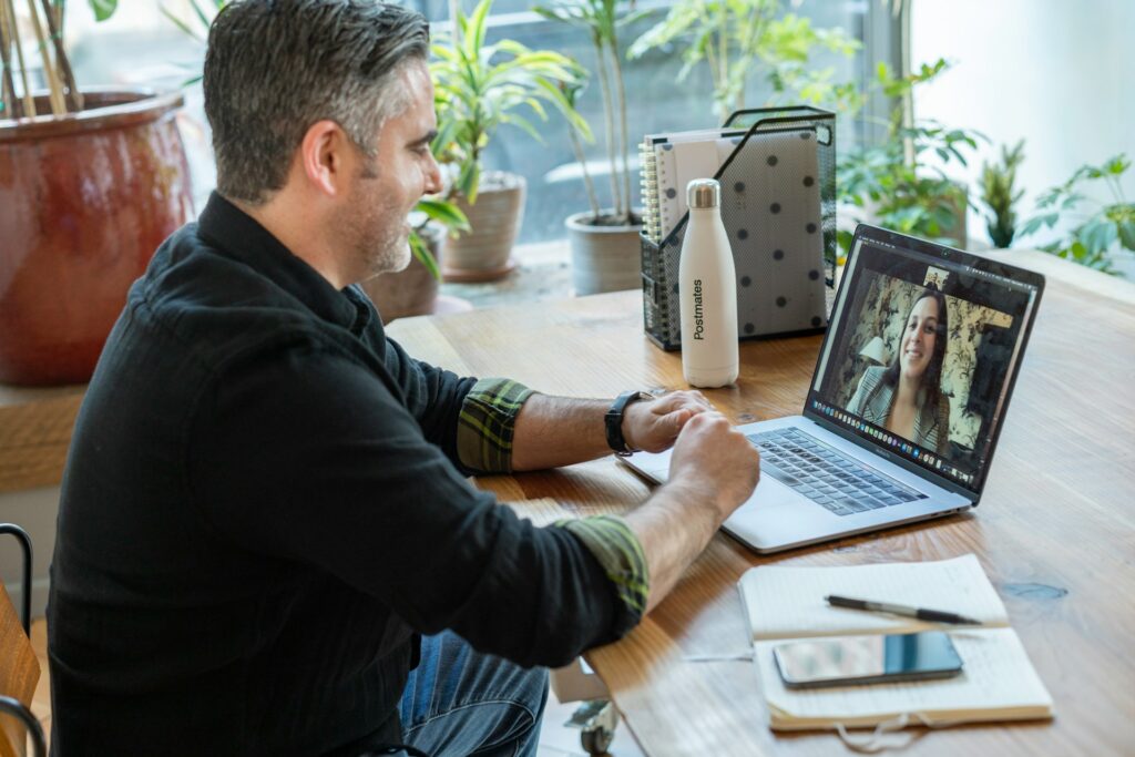 A man at home and woman in the office communicate on a video call using secure digital workspaces.