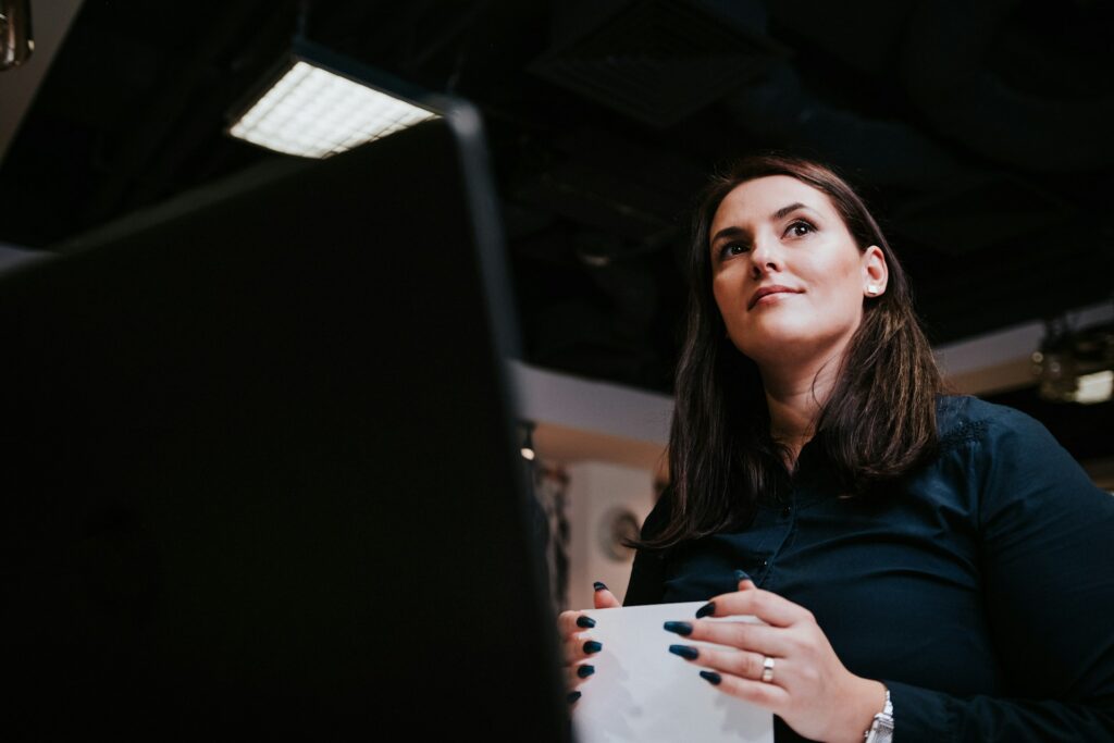 A professional woman smiles and looks away while scaling AI in financial services at a workstation