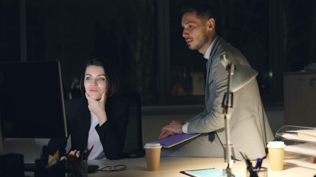 Two colleagues access their unified operating platform on a computer in an office at night.