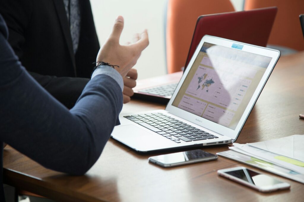 Two co-workers look at a third-party cyber risk map on a laptop in a conference room.