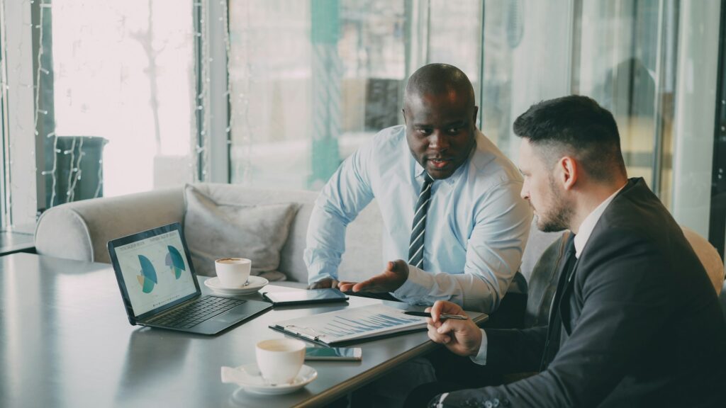 Two businessmen discussing agentic AI at a conference table with a laptop