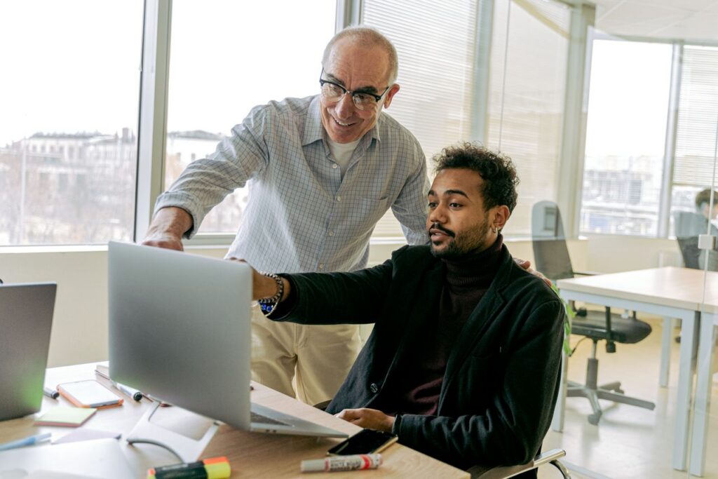 Colleagues collaborate in an open office environment, researching managed services on a laptop.