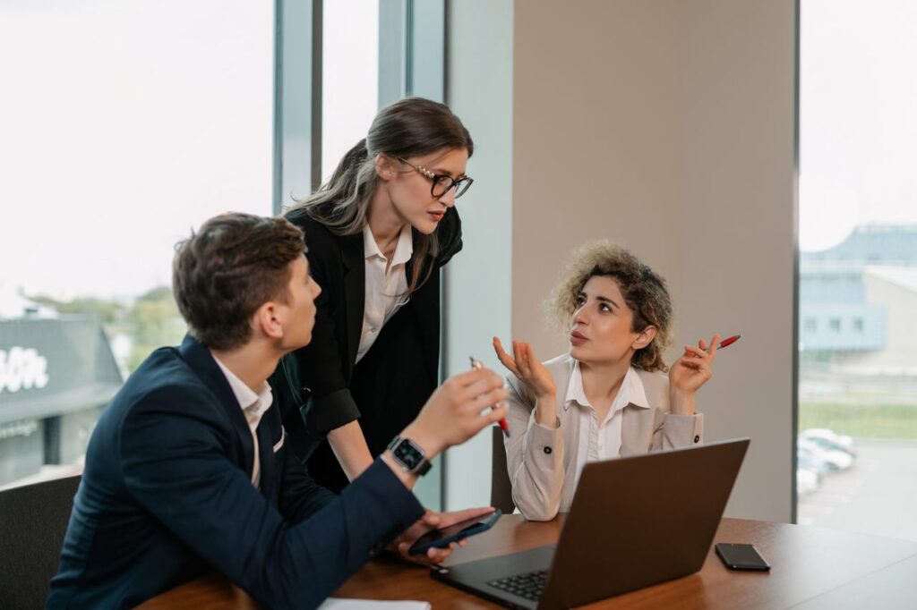 Three colleagues discuss treating cybersecurity as infrastructure in a conference room.